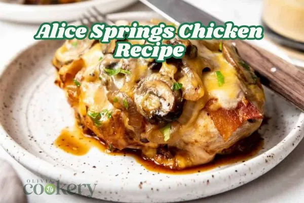 Alice Springs Chicken served on a rustic white plate, topped with sautéed mushrooms, melted cheese, crispy bacon, and chopped green onions.