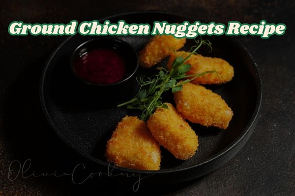 “A plate of crispy chicken nuggets with a golden breadcrumb coating, served with dipping sauce and garnished with fresh vegetables.”