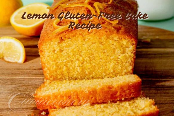 "A moist and fluffy gluten-free lemon cake layered with creamy lemon buttercream frosting, garnished with fresh lemon slices and lemon zest, presented on a white cake stand against a light background."